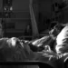 Image d'une personne en fin de vie dans un lit d'hôpital, entourée d'équipements médicaux, symbolisant la médicalisation et l'isolement dans les derniers moments de la vie.