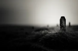 Une stèle funéraire isolée dans un paysage de cimetière brumeux, illustrant le rôle de la cartographie des cimetières dans la préservation de ce patrimoine historique.