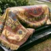 Sépulture de Rudolf Noureev recouverte d’un kilim oriental en mosaïque, photographiée dans un cimetière arboré. Le tombeau, en pierre noire, est orné de motifs colorés rappelant les tapis d’Orient.