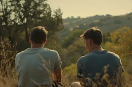 Deux hommes assis de dos dans une clairière paisible au coucher du soleil, image inspirée de The Endless, illustrant une atmosphère de répétition silencieuse et de fatalité existentielle, dans une lecture Memento-mori du temps et de l’enfermement.