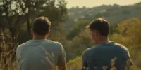 Deux hommes assis de dos dans une clairière paisible au coucher du soleil, image inspirée de The Endless, illustrant une atmosphère de répétition silencieuse et de fatalité existentielle, dans une lecture Memento-mori du temps et de l’enfermement.